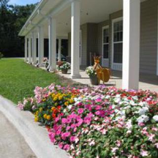 A vibrant flower garden alongside a porch with white columns.