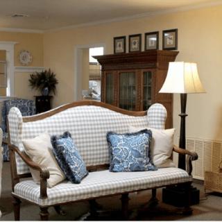 A cozy living room featuring a patterned sofa, decorative cushions, and a floor lamp beside a wooden cabinet.