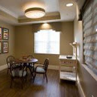 A cozy dining area with a table and chairs, complemented by warm lighting and window coverings.