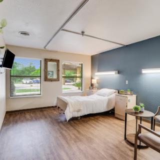 A well-designed hospital room featuring a twin bed, bedside tables, and ample natural light.