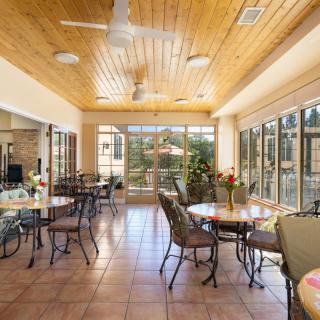 A bright dining area with wooden ceiling and glass walls featuring tables and chairs.