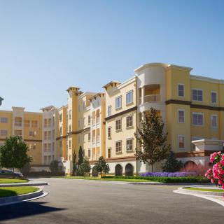 A sunny day view of a modern apartment building with landscaped surroundings.