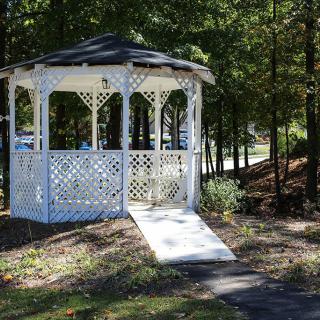 A white gazebo situated in a wooded park area.