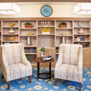 A cozy living room setup featuring stylish chairs and a well-organized bookshelf.