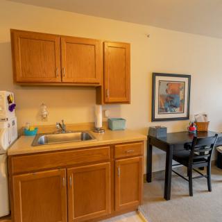 A cozy kitchen area with wooden cabinets, a sink, and a small dining table with chairs.
