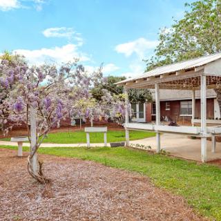A charming house with a lovely garden, featuring blooming flowers and a spacious patio.