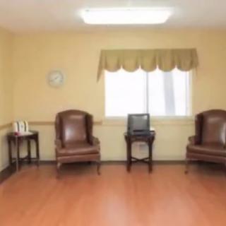 A simple waiting room with two chairs, a table, and a window.