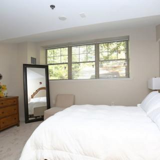 A bright and airy bedroom with a large window, comfortable bedding, and minimalist decor.