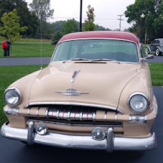 A stylish vintage car showcasing classic mid-century design with a golden body and red roof.