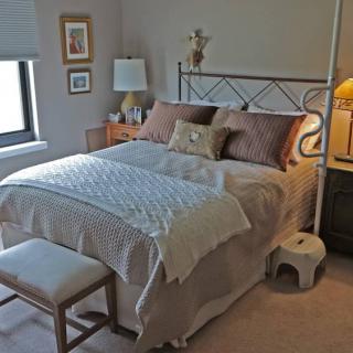 A cozy bedroom with a neatly made bed, nightstands, and soft lighting.