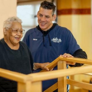 A caregiver assists an elderly person in a rehabilitation setting.