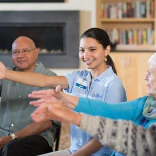 A healthcare provider guides a group of elderly individuals in a wellness exercise session.