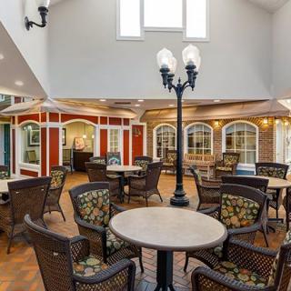 A well-lit interior space with arranged tables and chairs, featuring decorative architectural elements and soft lighting.