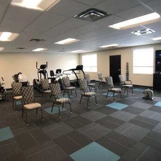 A spacious exercise room with chairs and various fitness equipment.