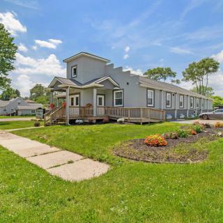 A single-story residential home with a well-maintained lawn and landscaping under a blue sky with scattered clouds.