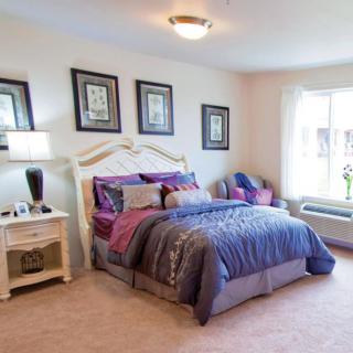 A cozy and well-decorated bedroom with a comfortable bed, side table, and artwork on the walls.