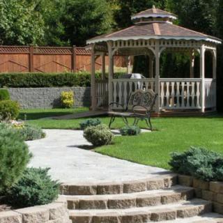 A tranquil garden featuring a gazebo and a well-maintained lawn with a stone pathway.