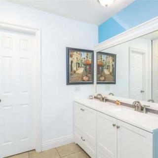 A modern bathroom with a double sink vanity, framed artwork, and a large mirror.