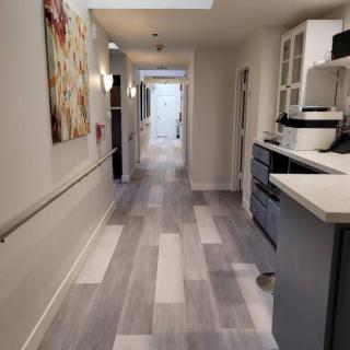 A modern hallway with a kitchen area and artwork displayed on the wall.