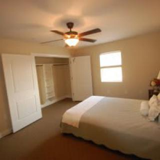 A cozy bedroom with a bed, carpet, and ceiling fan.