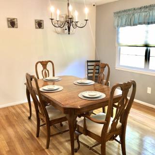 A cozy dining area with a wooden table set for four under a classic chandelier.