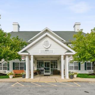 Front entrance of a building with a peaked roof and surrounding trees.