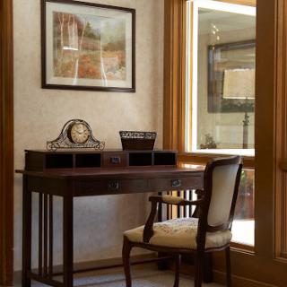 A cozy and elegant home office setup featuring a wooden desk and chair, complemented by natural light from the window.