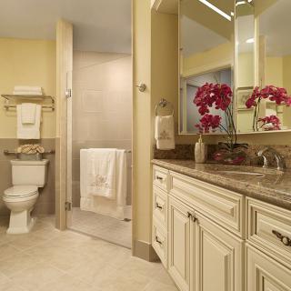 A well-appointed bathroom with elegant cabinetry, a large mirror, and a glass-enclosed shower.