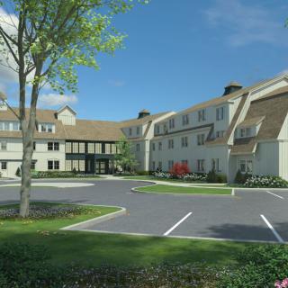 A residential building with a parking lot in the foreground, surrounded by trees and landscaping.