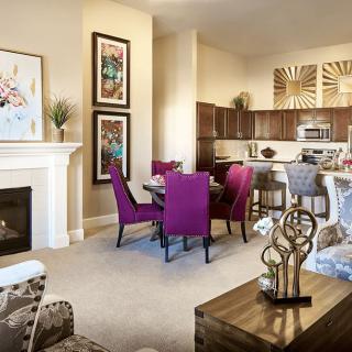 A modern living space featuring a dining area with purple chairs, a cozy fireplace, and an open-concept kitchen.