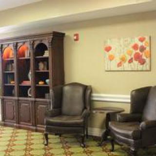 A cozy lounge area with leather chairs and a decorated bookshelf.