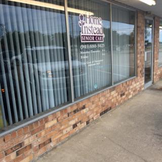 A storefront featuring large windows and a brick exterior, displaying a business sign.