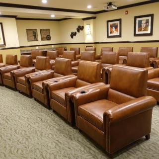 A luxurious home theater room featuring rows of brown leather recliner chairs.