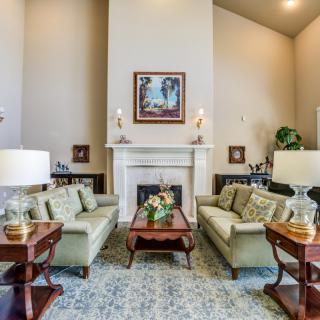 A well-designed living room featuring two sofas facing each other, a coffee table, and a fireplace with a painting above it.
