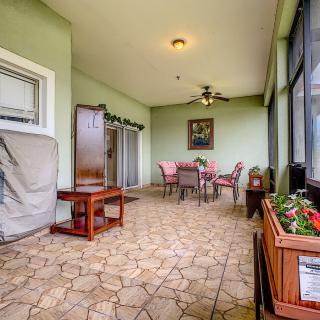 A cozy indoor patio featuring a dining table and chairs, surrounded by green walls and adorned with artwork and plants.