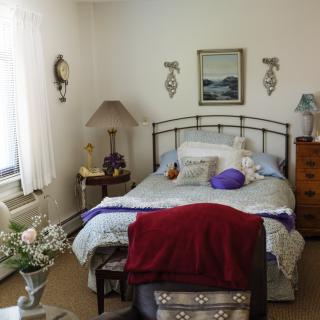 A cozy bedroom with a neatly made bed, lamps on side tables, and wall decorations.
