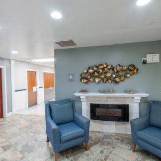 A modern lobby with blue chairs, wall art, and a fireplace.
