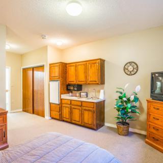 A cozy bedroom with wooden furniture and a small kitchenette area.