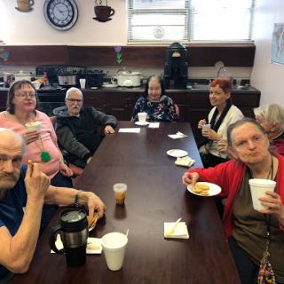 A group of seniors enjoying snacks and conversation around a table.