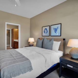 A cozy and well-decorated bedroom featuring a neatly made bed, nightstands with lamps, and framed artwork on the wall.