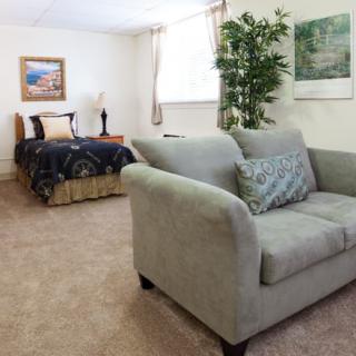 A cozy bedroom with a sofa and bed, featuring neutral decor and natural light.