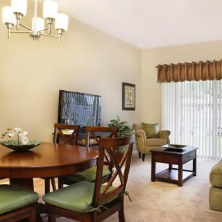 A cozy living and dining area featuring a wooden dining table with chairs, a comfortable seating arrangement with sofas and armchairs, and elegant window treatments.