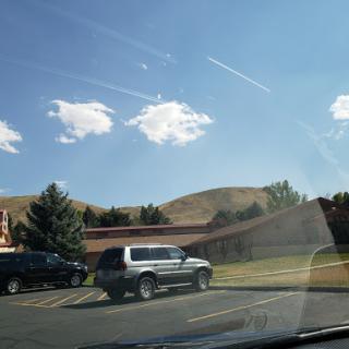 A sunny day with scattered clouds over a parking lot and rolling hills.