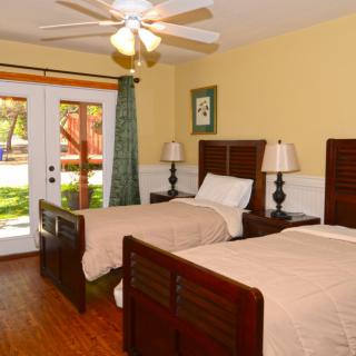 A cozy bedroom with twin beds, a ceiling fan, and French doors leading outside.