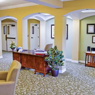 A welcoming office reception area with a desk, plants, and hallway in the background.