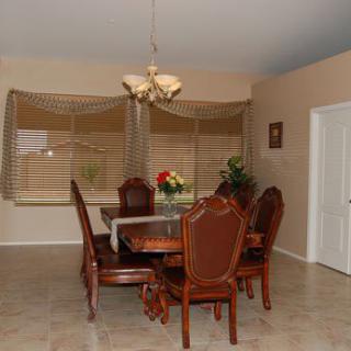 A dining room with a wooden table, chairs, chandelier, and decorative plants.