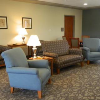 A cozy living room with chairs, a sofa, and lamps.