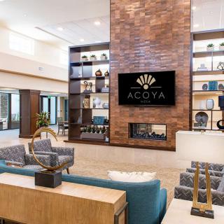 A modern lobby with stylish furniture, a brick feature wall, and decorative shelves.