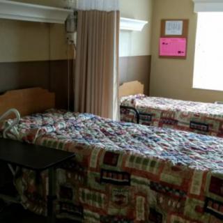 A hospital room with two beds, separated by a privacy curtain.