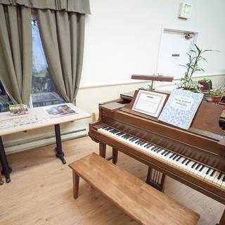 A cozy music room featuring a piano with sheet music, alongside a wooden bench and potted plants.